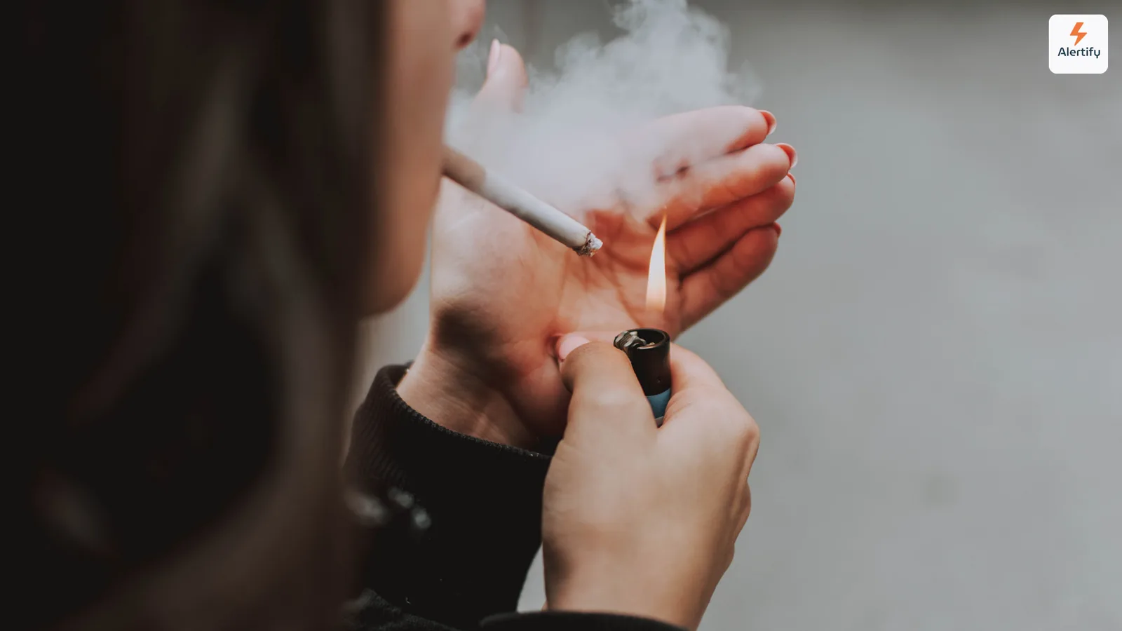 Persona che accende una sigaretta in casa con il fumo che si arriccia intorno alle mani
