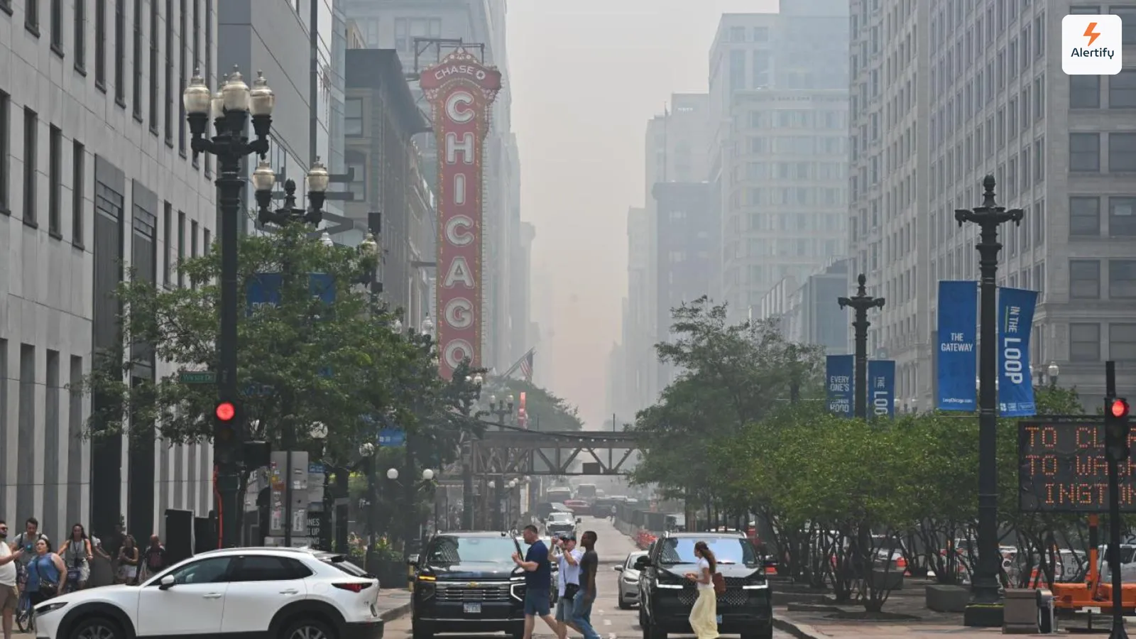 Foschia da incendi che inghiotte gli edifici lungo una strada di Chicago, con l'insegna del Chicago Theatre illuminata in primo piano.