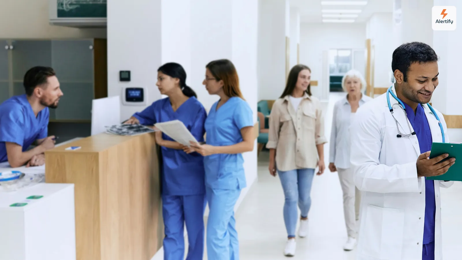 Personale sanitario e visitatori passano davanti al banco accettazione nella luminosa hall di un ospedale